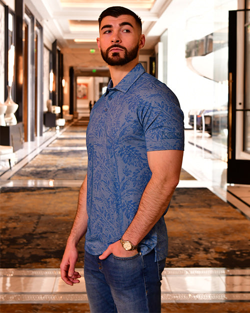 Man wearing blue polo with palm leaf print and Post Oak embroidery in Post Oak Hotel.