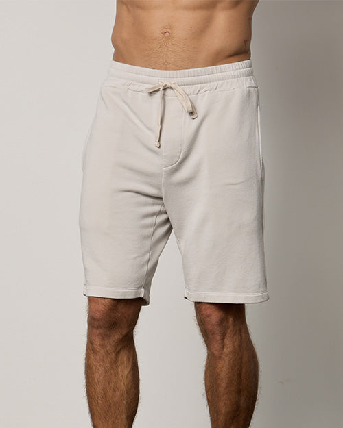 Model wearing cream-colored shorts with drawstring and pockets.