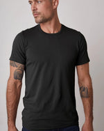 Model wearing Howard Men's Tee in black in front of white background.