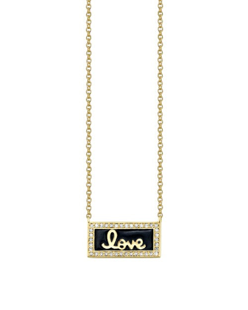 Gold necklace with diamond, gold, and black enamel charm that says "love" in cursive. 