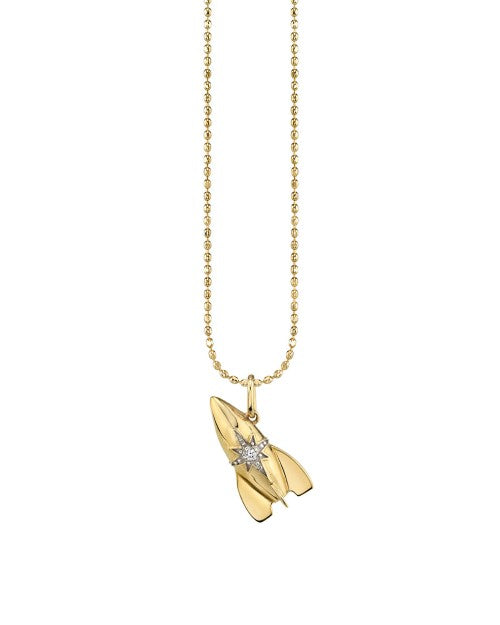 Gold necklace with rocket charm that has diamond accents. 